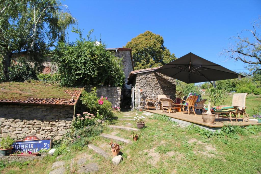 een huis met een paraplu en twee honden in de tuin bij Kernad in Bersac-sur-Rivalier