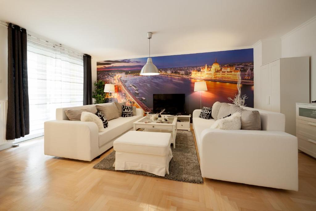 ein Wohnzimmer mit weißen Möbeln und einem Gemälde an der Wand in der Unterkunft GDE Holló Apartments in Budapest