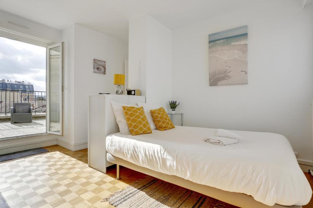 une chambre blanche avec un lit et un balcon dans l'établissement Le Nid du Roi - Appartement terrasse - Versailles, à Versailles