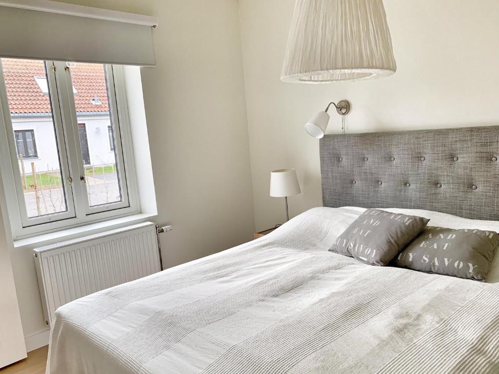 a bedroom with a large white bed and a window at Familjevänligt hus med pool och tennisbana in Torekov