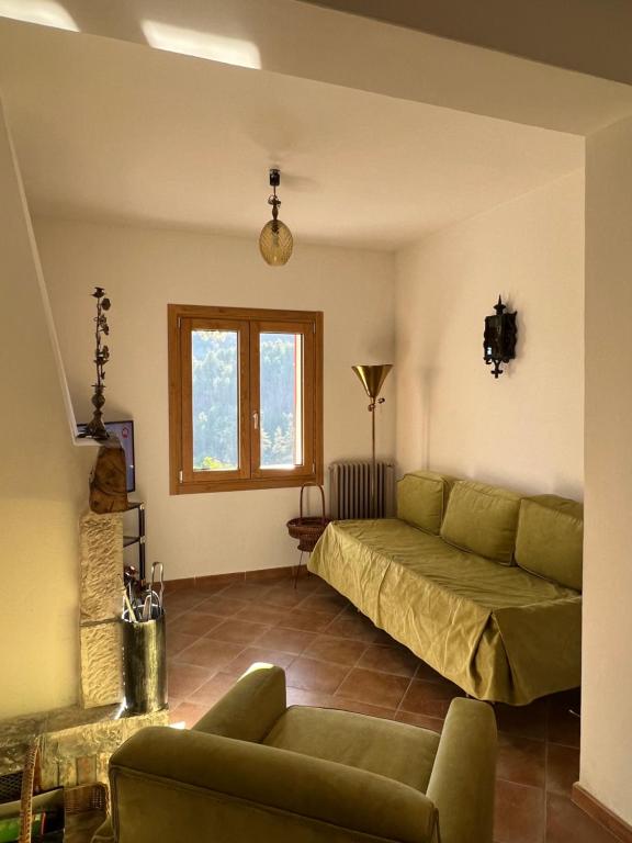 a living room with a green couch and a window at Casa vacanze “La baita” in Roccaraso