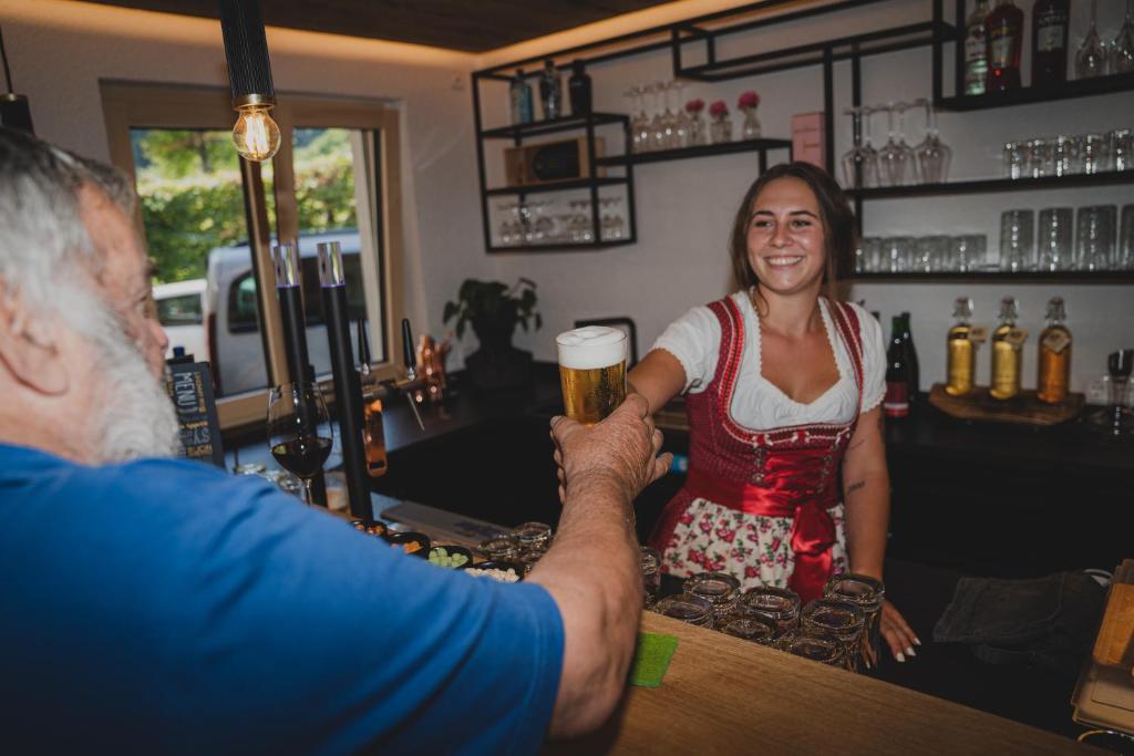 un hombre y una mujer sentados en un bar con una cerveza en Haus Vilgrassa, en Sankt Gallenkirch