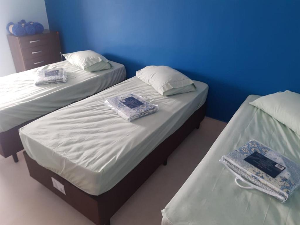 two twin beds in a room with blue walls at Apartamento Duplex pé na areia em Boracéia in Bertioga