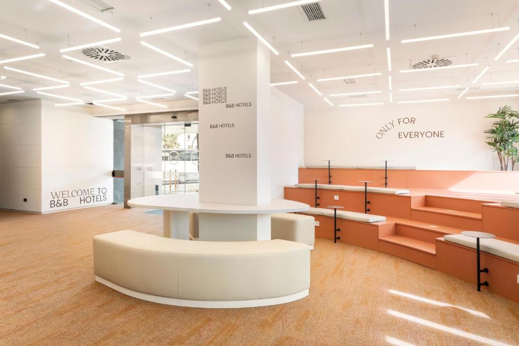 une salle d'attente avec une table et des bancs dans l'établissement B&B HOTEL Granada Estación, à Grenade