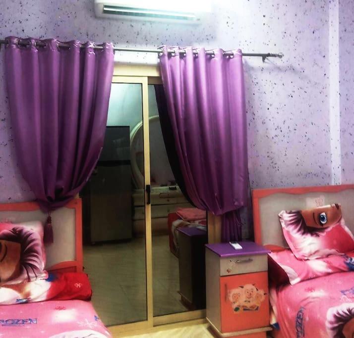 Habitación con 2 camas y cortinas moradas. en App12 - RAWDA - Enjoy the privacy of staying in a quiet apartment with free Wi-Fi as your complete second home in the heart of Hurghada, en Hurghada
