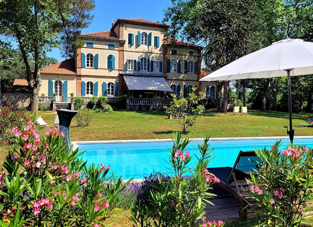 een groot huis met een zwembad en een parasol bij Oh, le château! in Almayrac