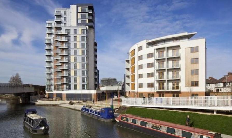 a boat in a river next to a building at Lovely luxury 1-Bed Apartment in Wembley in London