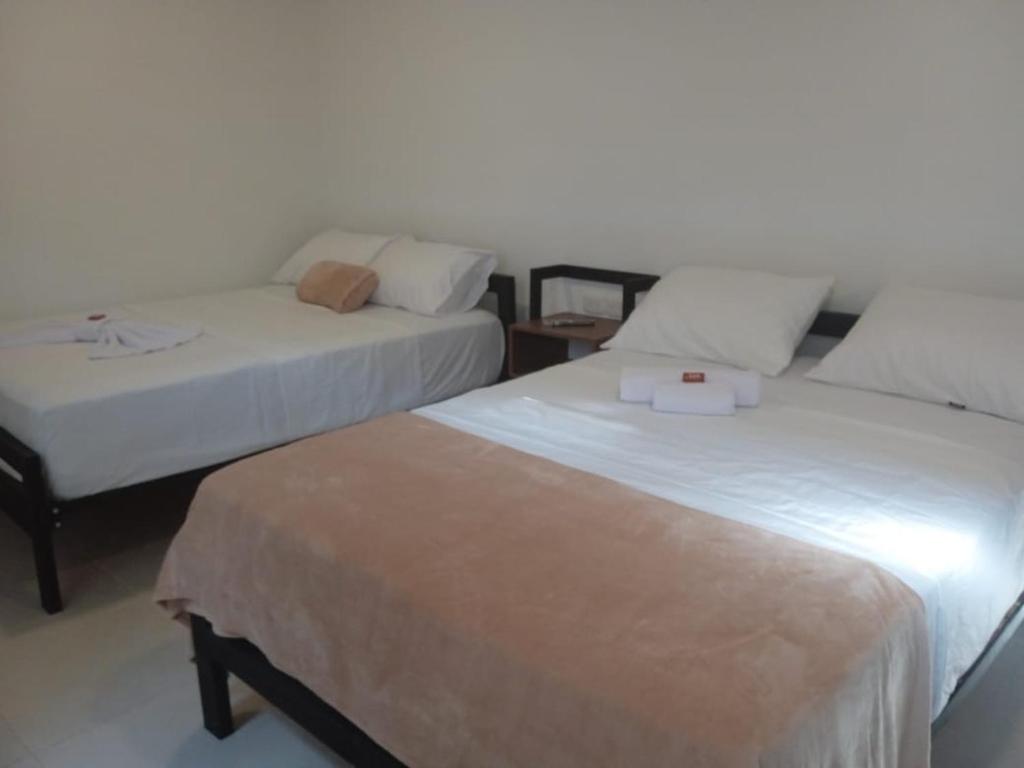 duas camas sentadas uma ao lado da outra num quarto em Hotel El Baquiano em San Juan de Arama