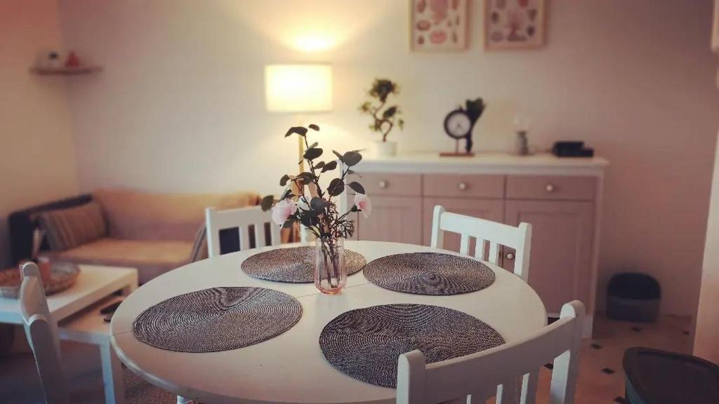 una mesa de comedor con platos y un jarrón de flores. en Une parenthèse à dives sur mer, en Dives-sur-Mer