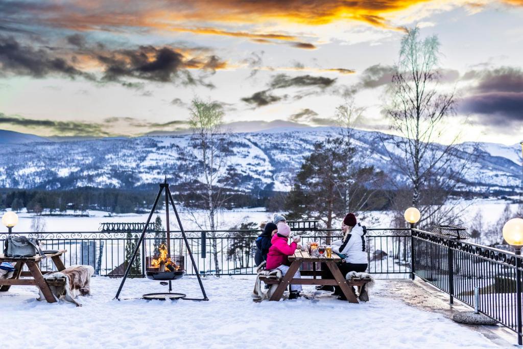 um grupo de pessoas sentadas numa mesa na neve em Straand Hotel em Vradal