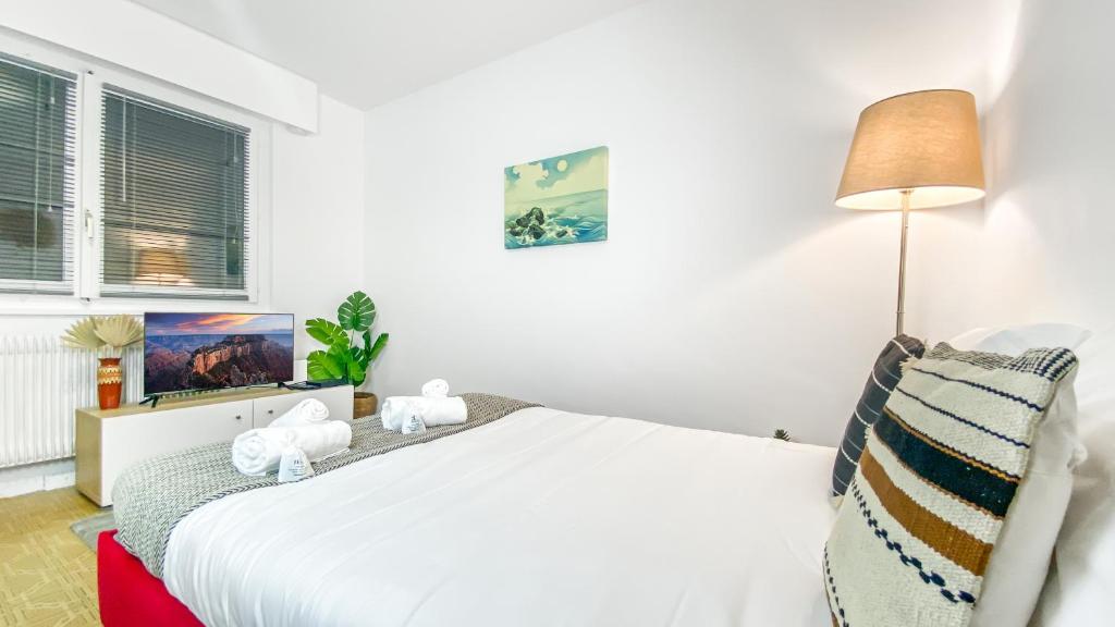 a bedroom with a white bed and a lamp at Homey AWAY - Centre-ville &#47; Au Calme &#47; Proche des transports pour Genève in Annemasse