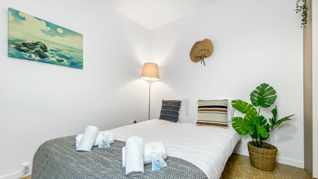 a bedroom with a bed with white sheets and a plant at Homey AWAY - Centre-ville &#47; Au Calme &#47; Proche des transports pour Genève in Annemasse