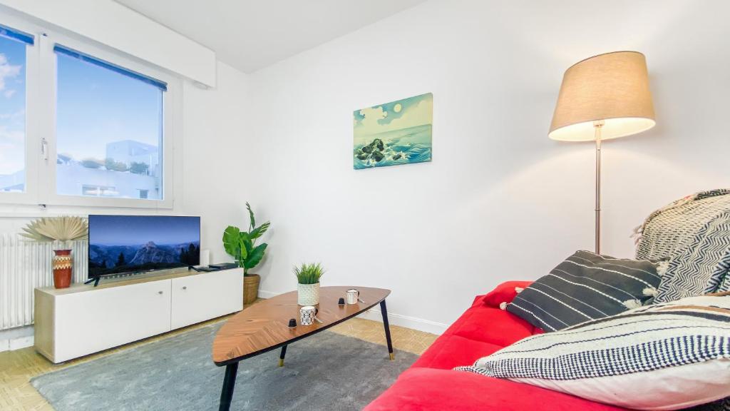 a living room with a red couch and a tv at Homey AWAY - Centre-ville &#47; Au Calme &#47; Proche des transports pour Genève in Annemasse