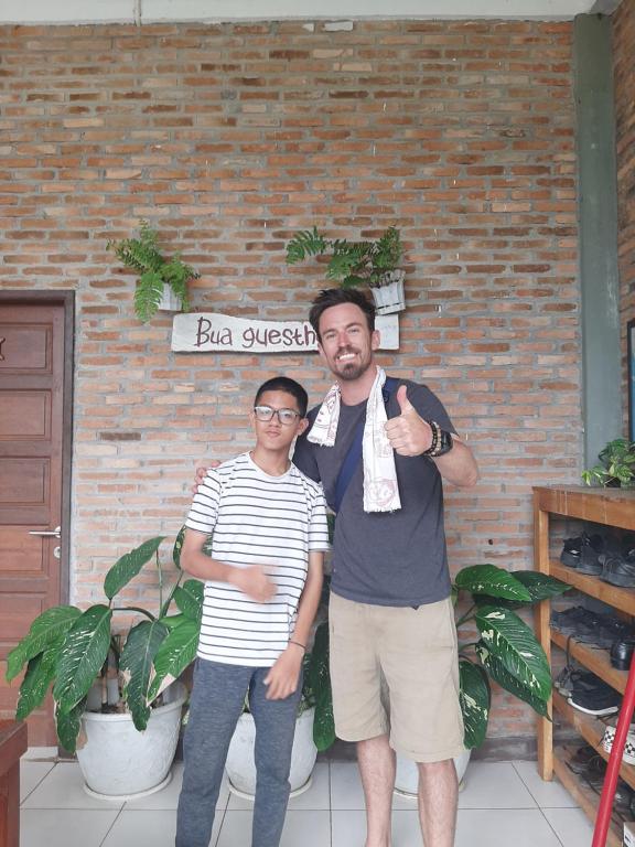 a man and a woman standing in front of a brick wall at Bua Guest House in Medan
