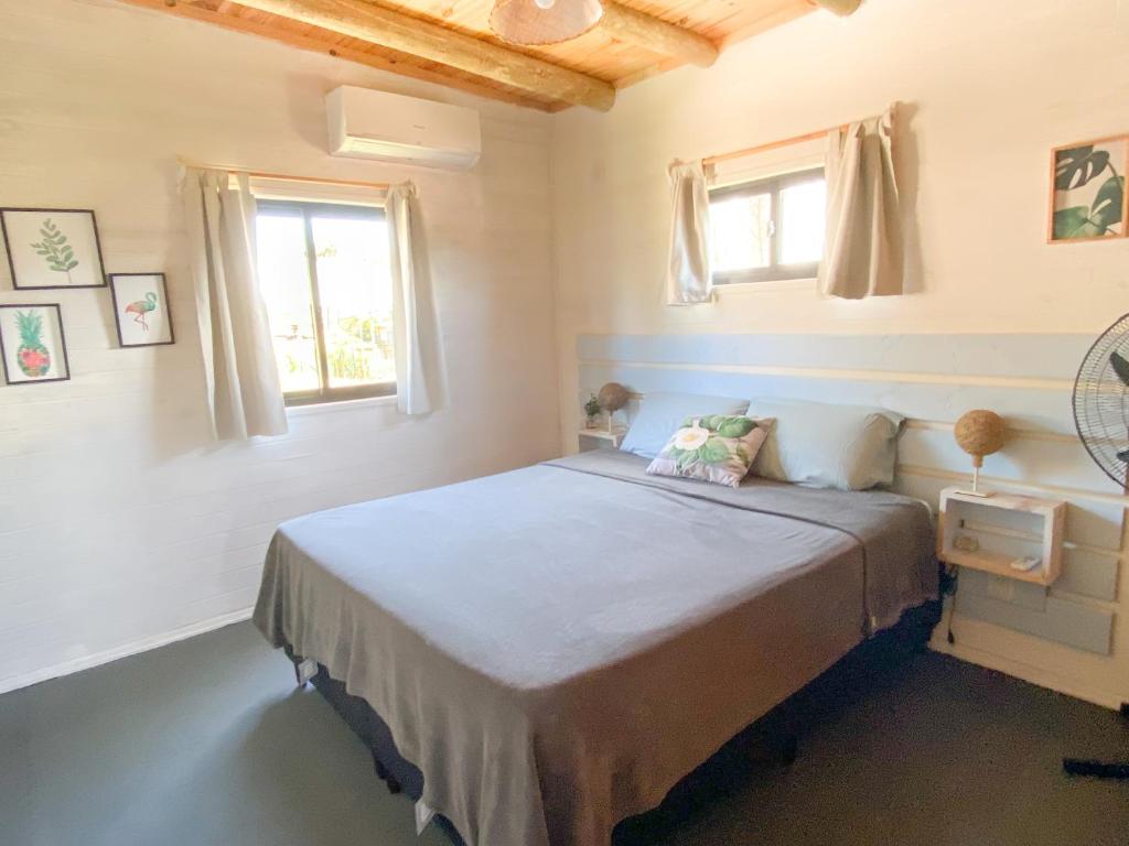 1 dormitorio con 1 cama grande y 2 ventanas en Mandalas de Mar en Punta Del Diablo