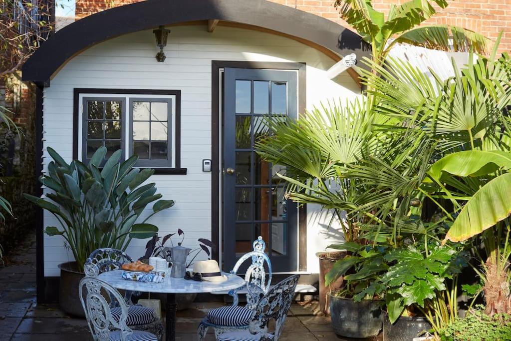 a house with a table and chairs in front of a door at The Cabana - a romantic seaside getaway and garden in Ryde
