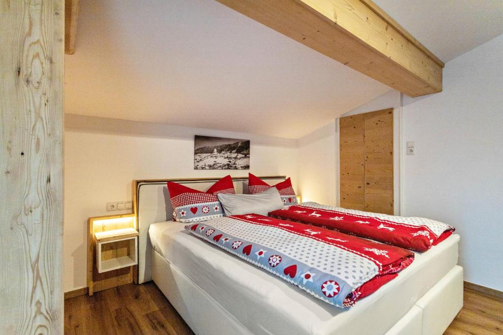 - une chambre avec un lit doté d'oreillers rouges et blancs dans l'établissement Bergwelt B, à Niederau