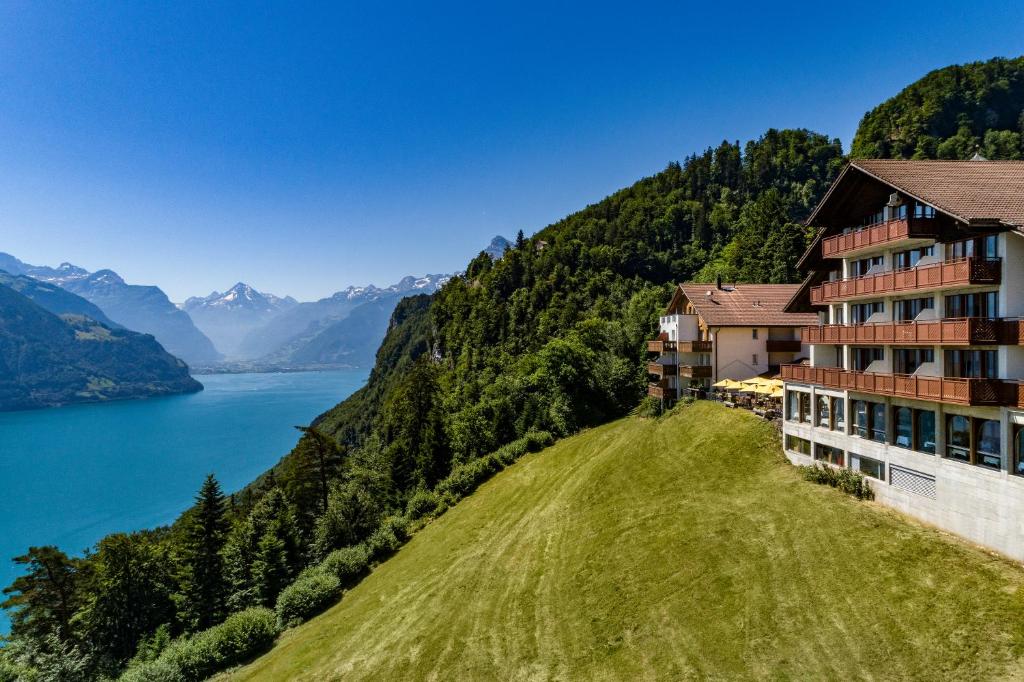 a hotel on a hill next to a body of water at Hotel und Naturhaus Bellevue in Seelisberg