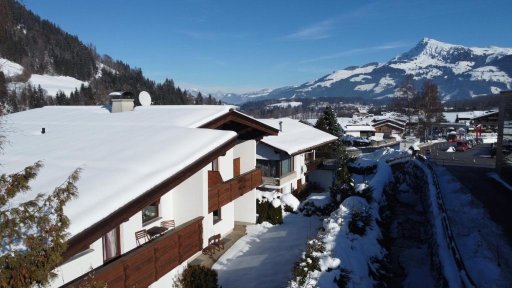 a house with snow on the roof with a mountain at Fleckalm Chalets in Kirchberg in Tirol