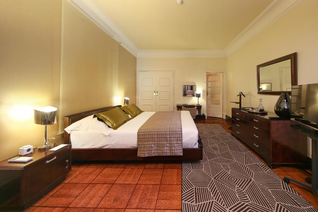 A spacious classic bedroom with a television cabinet, dresser, and broad bed.