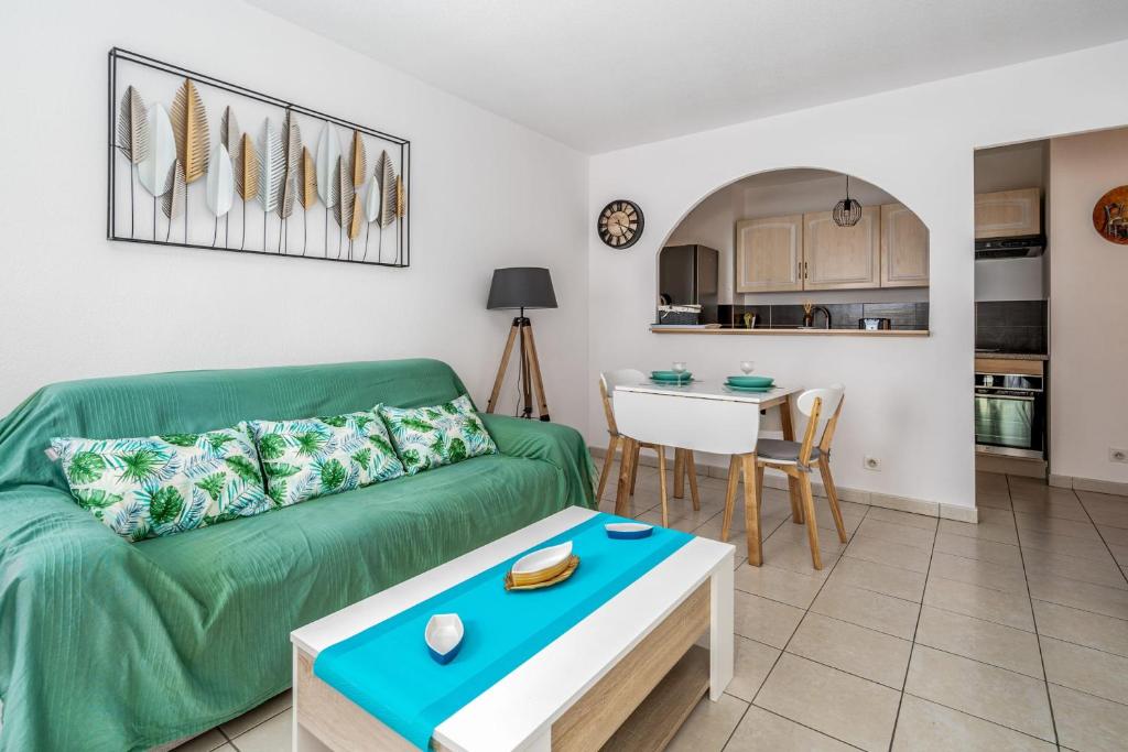 un salon avec un canapé vert et une table dans l'établissement Appartement Libériade - Welkeys, à Cannes