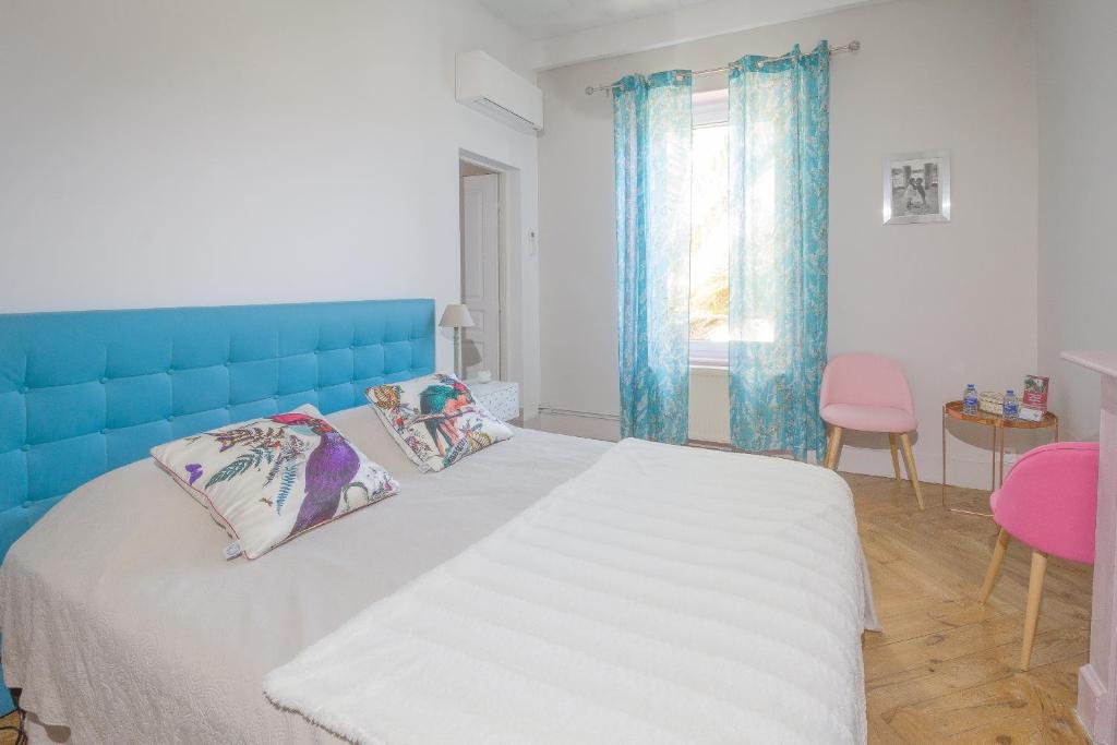 Schlafzimmer mit einem großen Bett mit blauem Kopfteil in der Unterkunft La Maison Grenadine près du canal du midi in Tourouzelle