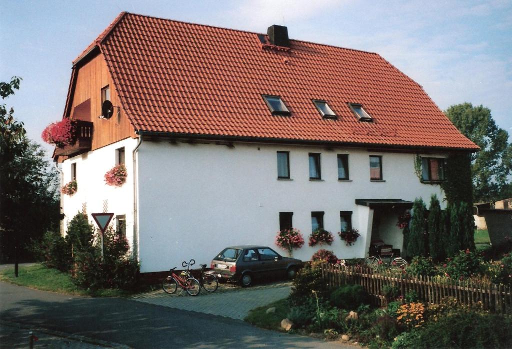 a white house with a red roof and a car at Zum Hecht, FeWo Spitzberg in Herrnhut