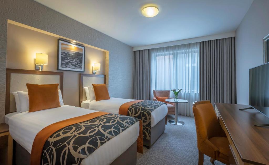 a hotel room with two beds and a desk at Clayton Hotel Belfast City in Belfast
