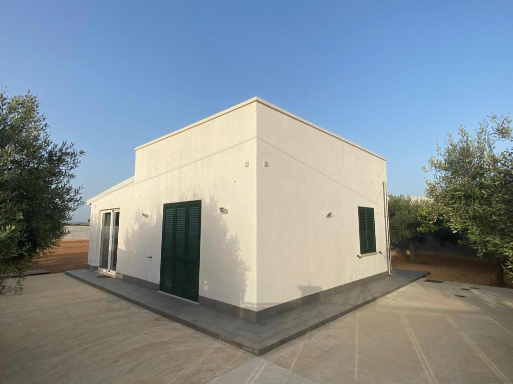 un edificio blanco con una puerta verde y árboles en La casetta degli ulivi, en Petrosino