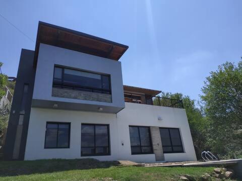 Casa blanca grande con ventanas negras en Casa en Villa Carlos Paz en Villa Carlos Paz