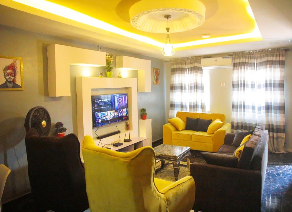 sala de estar con sillas amarillas y TV en A' BASICS APARTMENTS & SUITES, en Ibadán