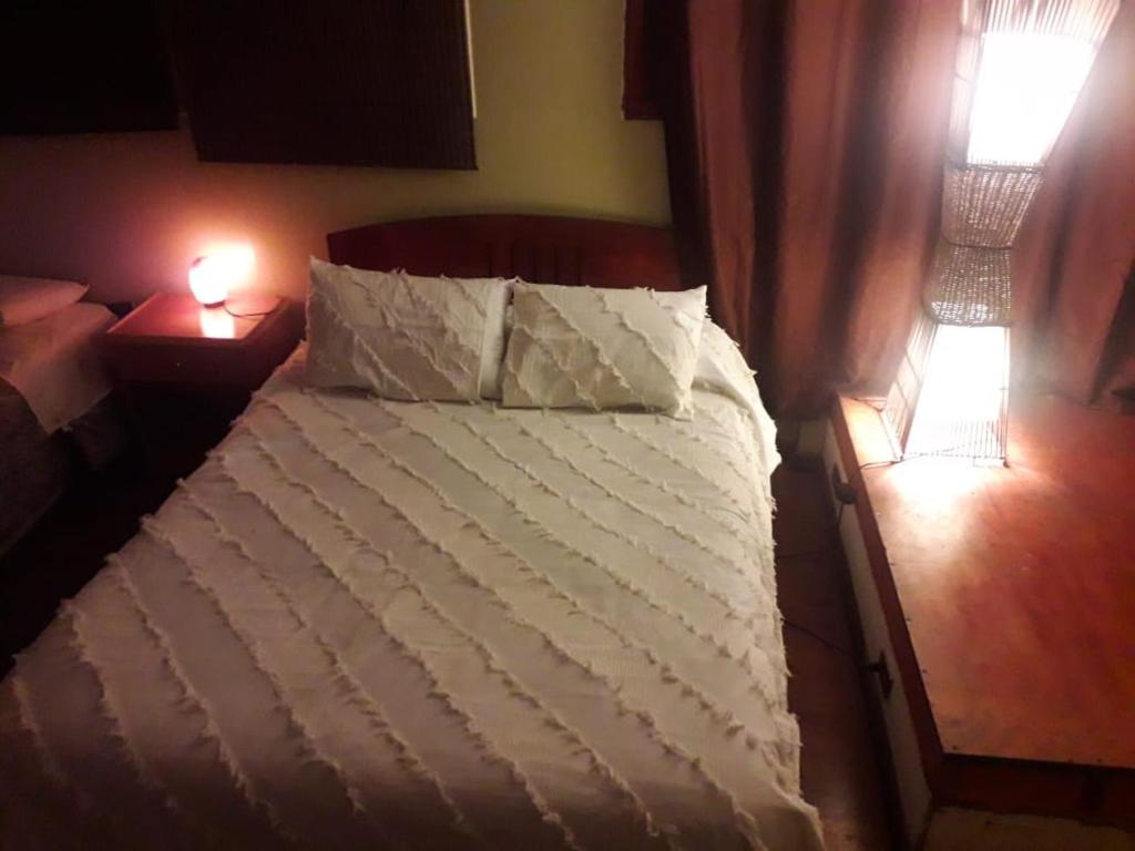 Una cama con sábanas blancas y almohadas en un dormitorio en apartamento gamboni, en Iquique