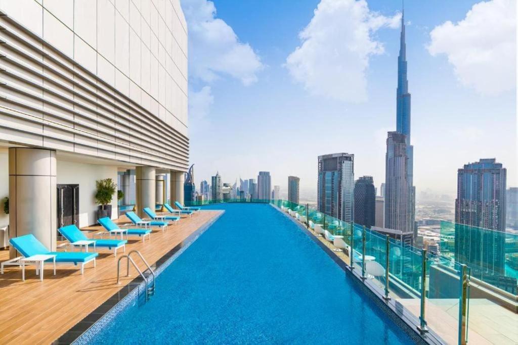 a swimming pool on the roof of a building with a city skyline at Paramount Hotel Midtown Flat with Burj Khalifa View in Dubai