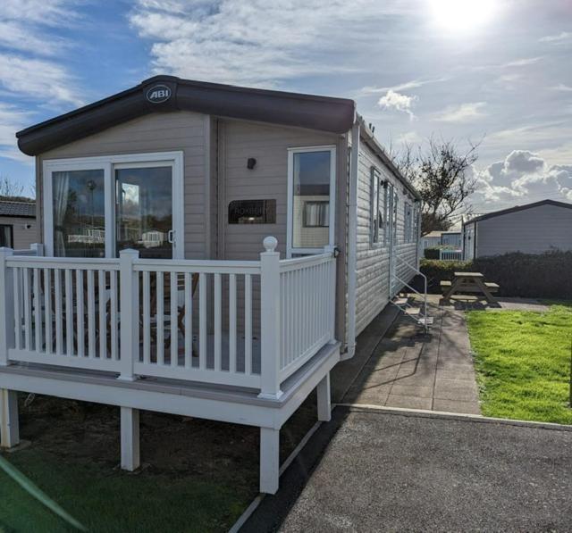 ein kleines Haus mit einem weißen Geländer und einer Veranda in der Unterkunft PEACEFUL HOMELY Caravan IN LOVELY CUL DE SAC Littlesea Haven Weymouth in Weymouth