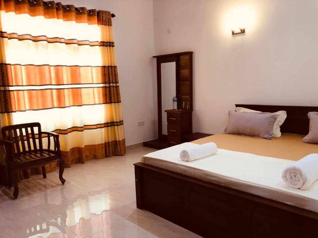 a bedroom with two beds and a chair and a window at Sanrish Airport Villa in Negombo