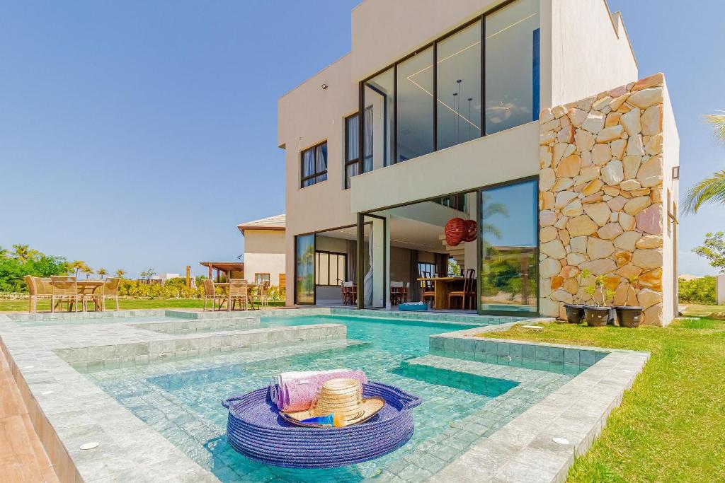 Villa con piscina frente a una casa en SA07 Maravilhosa Casa 5 Suítes - Reserva de Sauípe en Costa do Sauipe