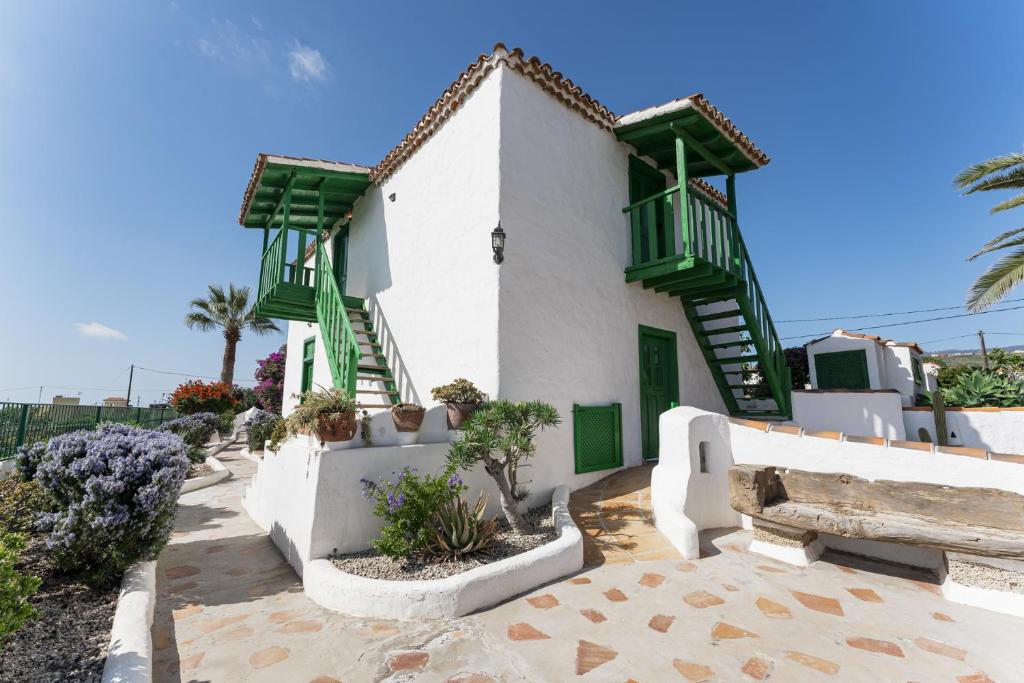 a white building with green doors and stairs on it at Casa Rural La Capellania in Granadilla de Abona
