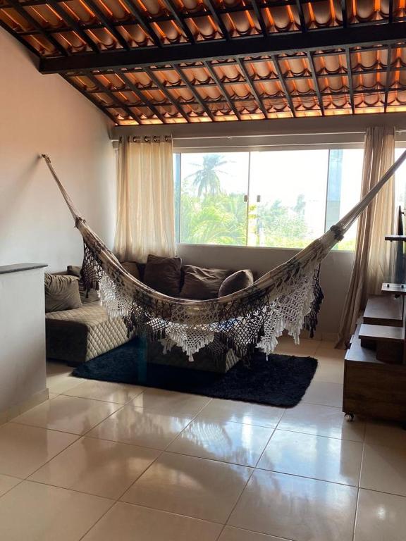 a hammock in a living room with a couch and a window at Ilha do amor in Camocim
