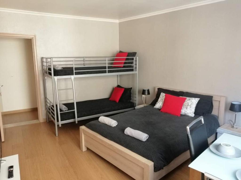 ein Schlafzimmer mit einem Bett und Etagenbetten mit roten Kissen in der Unterkunft Chambre 2/4p confortable in Ostende