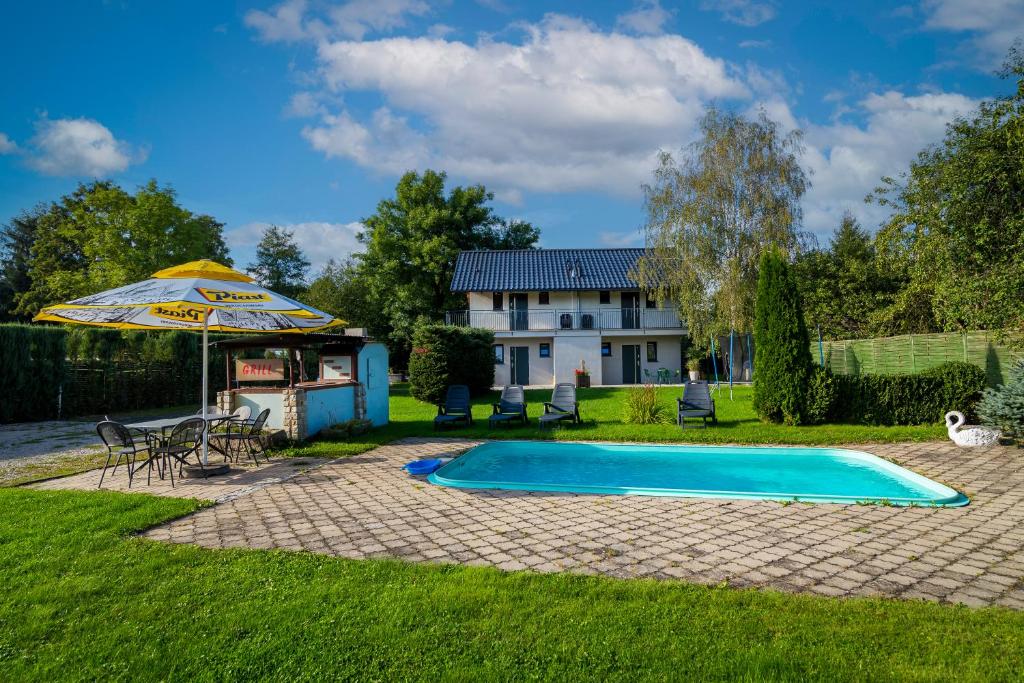 a swimming pool with an umbrella and a house at Apartament Marta in Kudowa-Zdrój