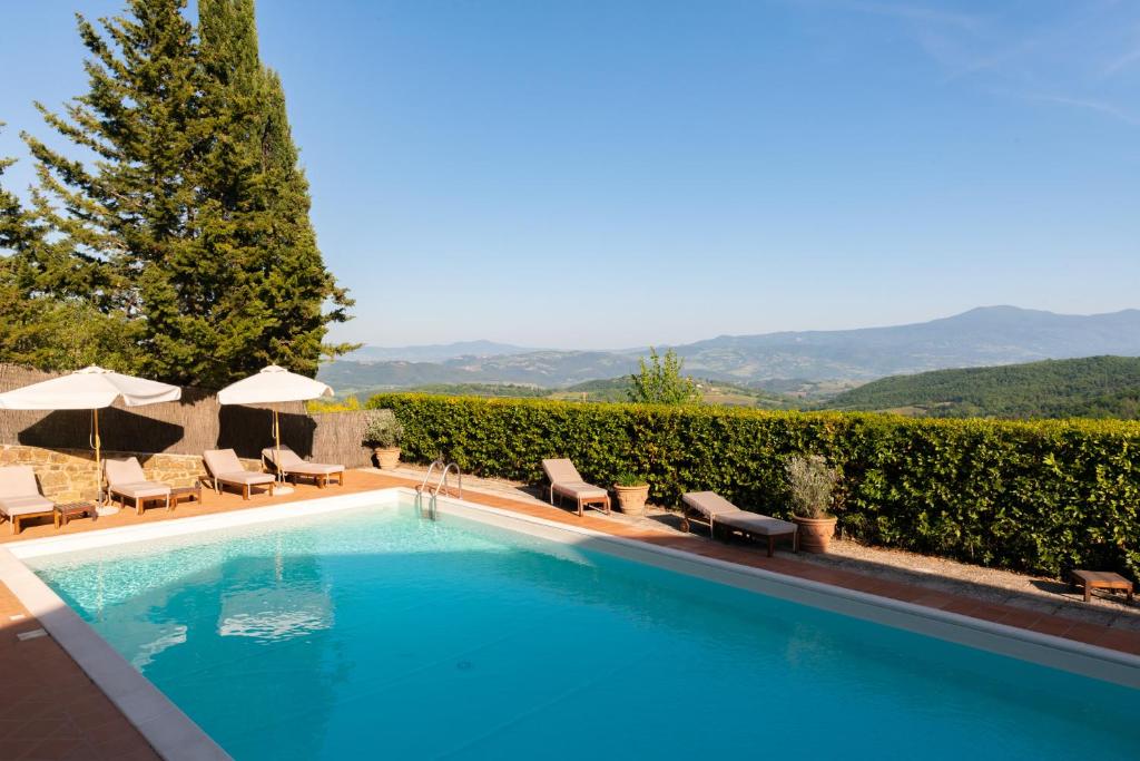 una piscina con sedie e ombrelloni accanto al resort di Si Montalcino Hotel a Montalcino