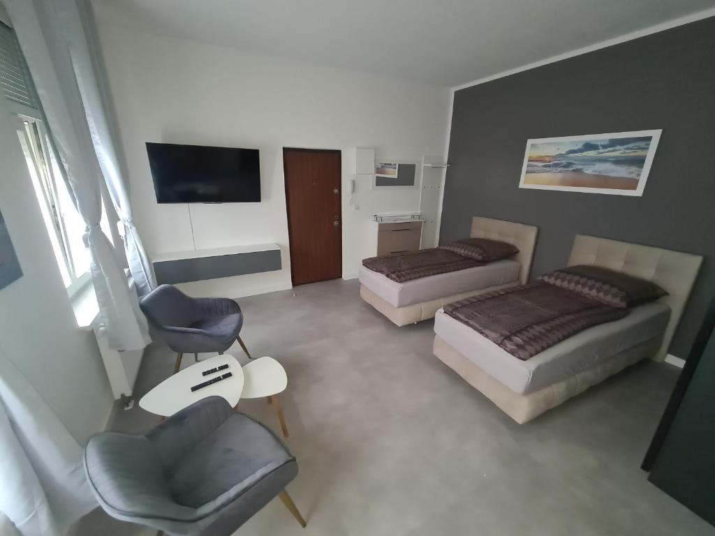 a room with two beds and a chair and a tv at Apartament Suite 1 in Bernburg