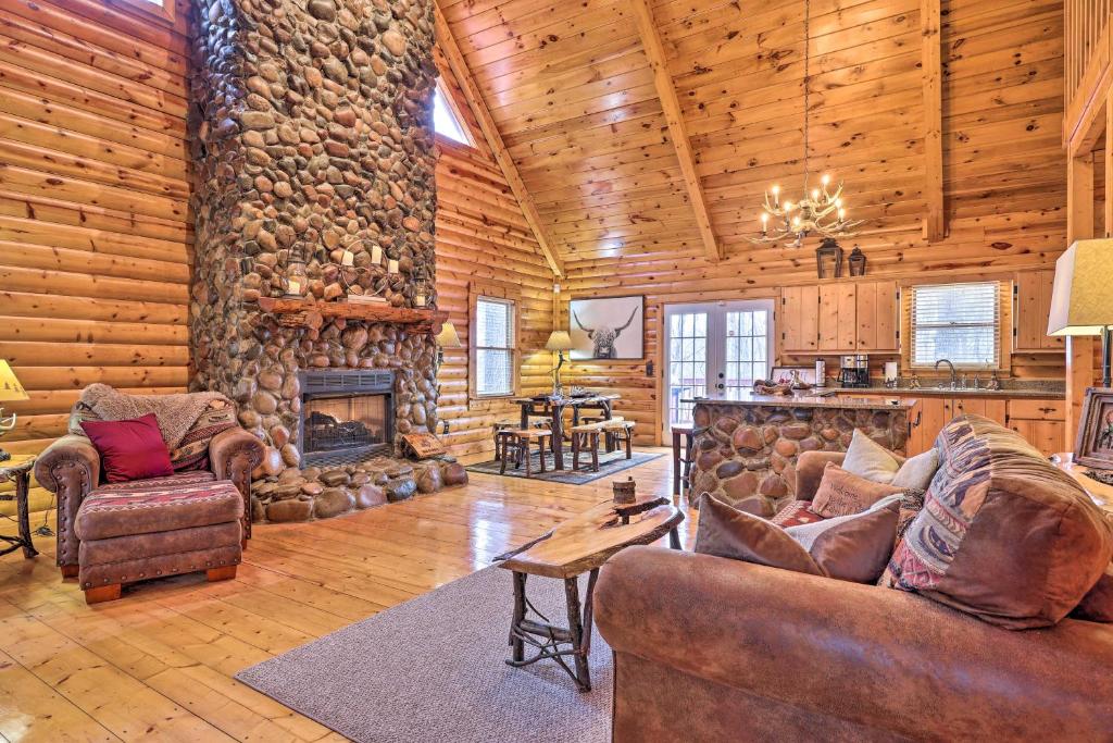a living room with leather furniture and a stone fireplace at 'Sleeping Bear Cabin' Coosawattee! Dog Friendly! in Ellijay
