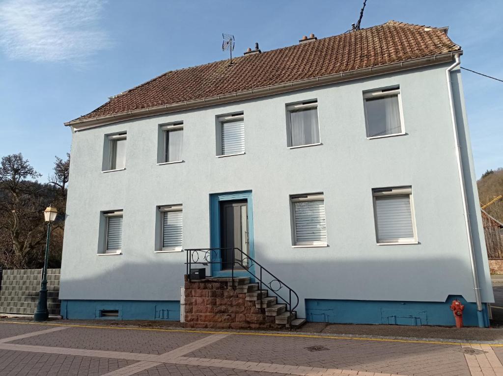ein weißes Gebäude mit blauer Tür auf einer Straße in der Unterkunft Gite du moulin in Gunsbach