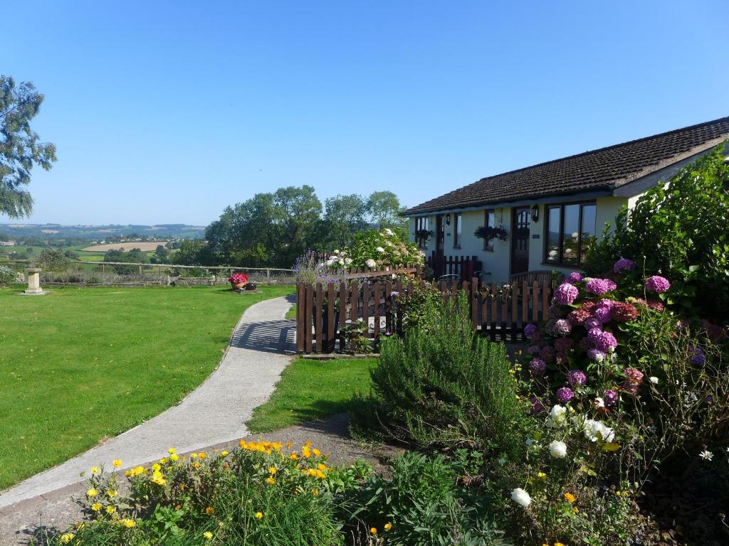 una casa con un jardín con flores delante en The Rock self-catering holiday cottage and garden lodges, en Coleford