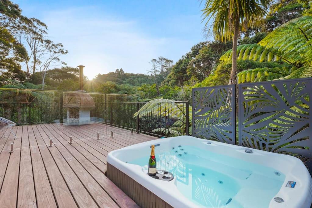 a bath tub on a wooden deck with a bottle of champagne at Tranquil Sunset Retreat - Spa - WIFI - Netflix in Auckland