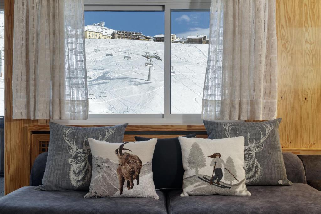un soggiorno con divano, cuscini e finestra di HelloChalet - The View - Ski to door with Matterhorn view a Breuil-Cervinia