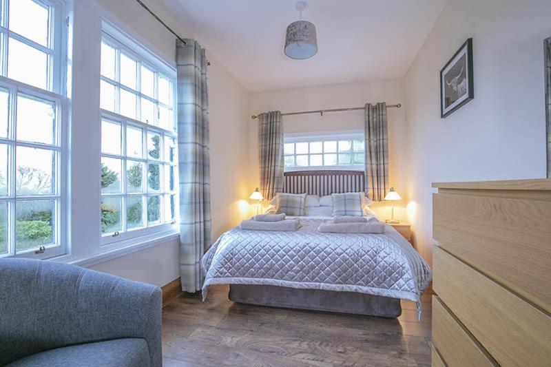 1 dormitorio con 1 cama y 2 ventanas en Craigievern Cottage, en Drymen