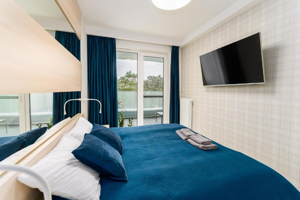 sypialnia z niebieskim łóżkiem i telewizorem z płaskim ekranem w obiekcie Sunrise Apartament w Rogowie