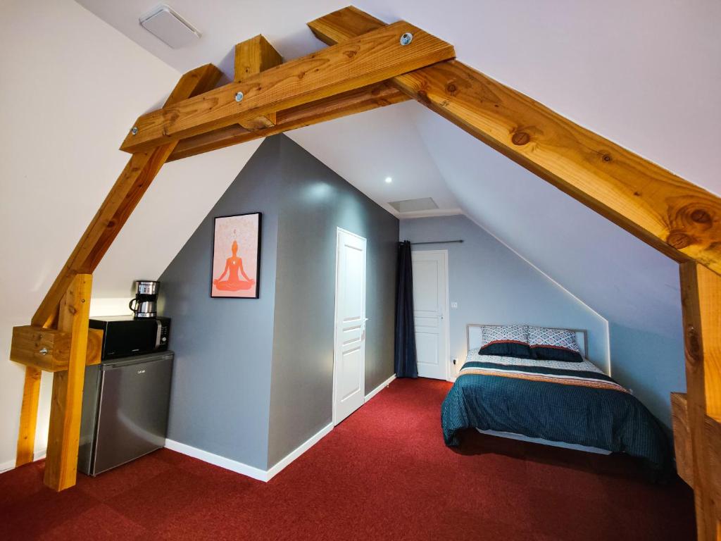 1 dormitorio en el ático con 1 cama y techo de madera en Gîte Les Grandes Menières près du Pal, en Le Donjon